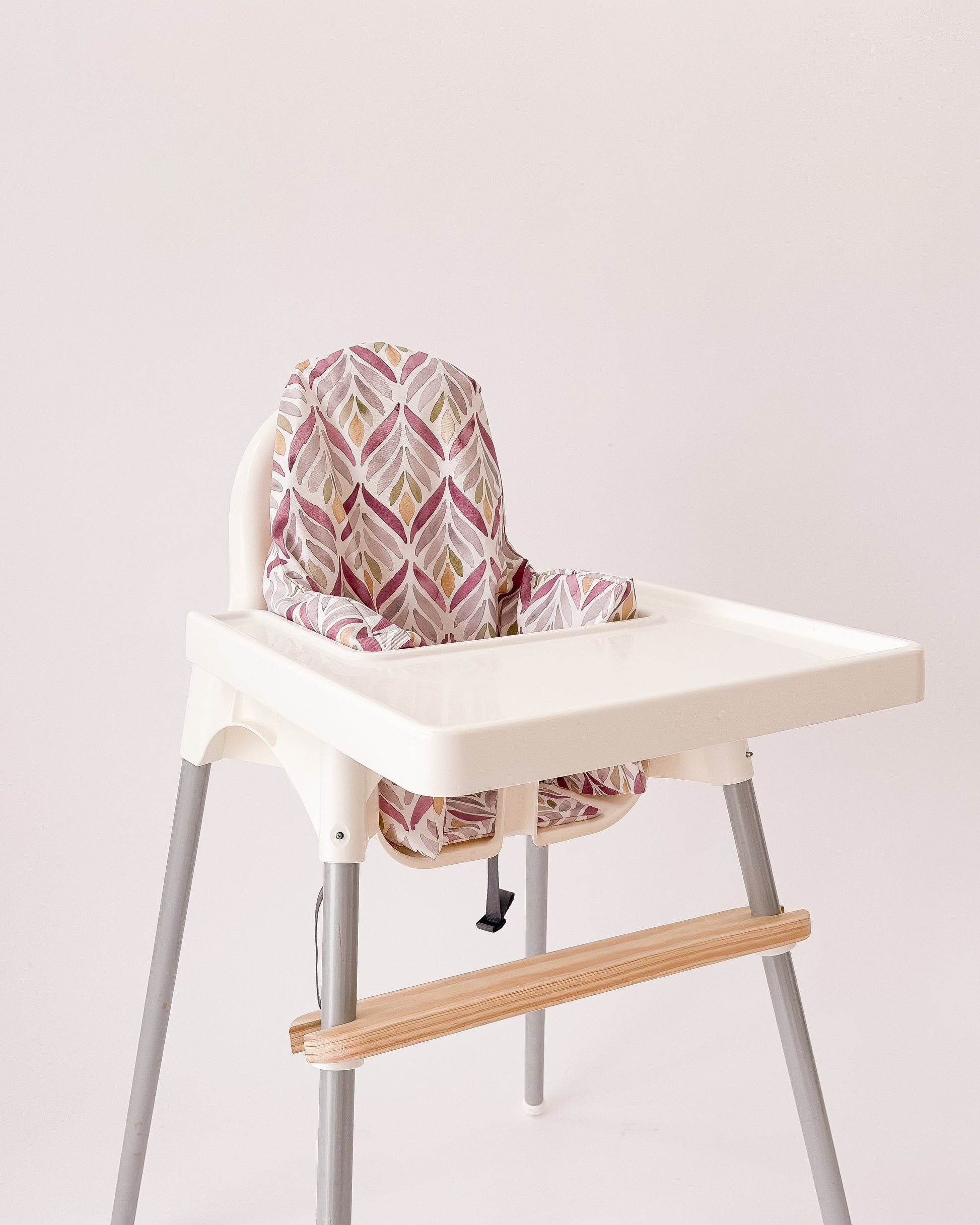 Capa padrão coral instalada numa cadeira infantil de refeição.