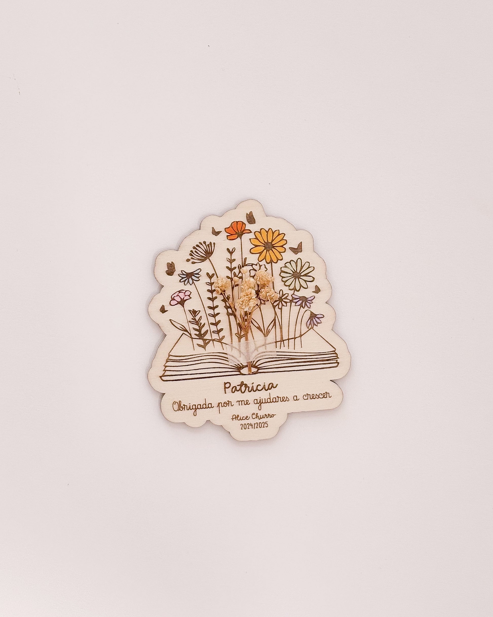 Placa de agradecimento para professores com nome gravado e arranjo de flores secas.