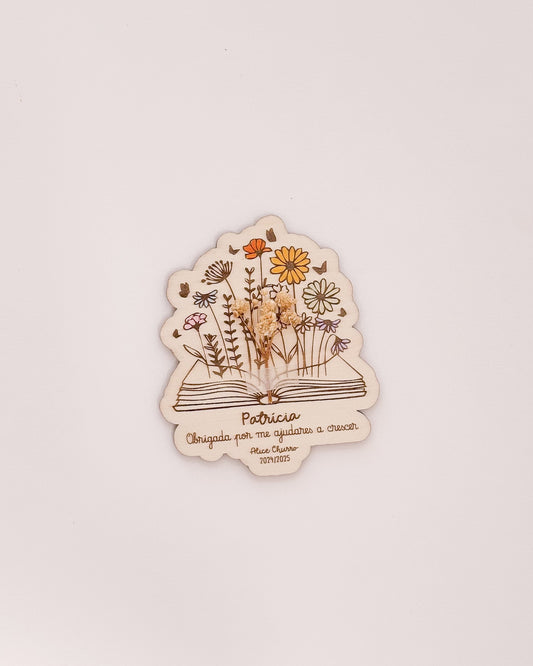 Placa de agradecimento para professores com nome gravado e arranjo de flores secas.