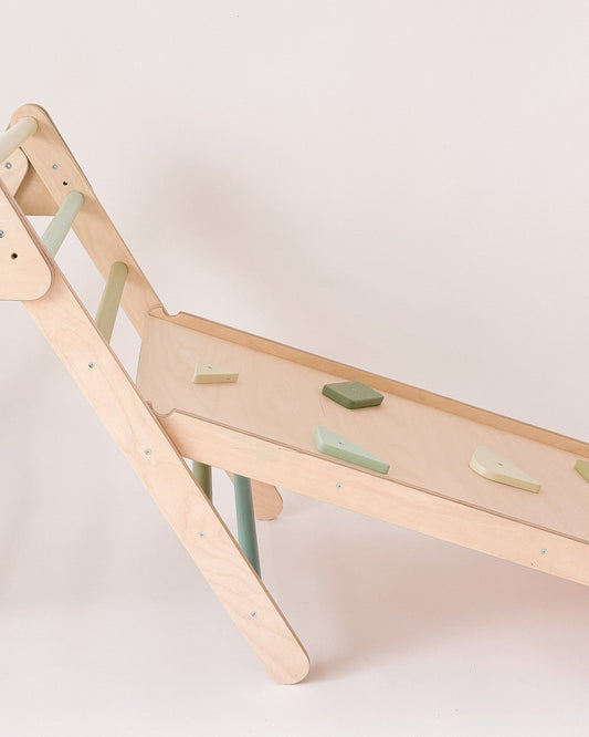 Rampa infantil encaixada num triângulo de Pikler, ideal como complemento de escalada.