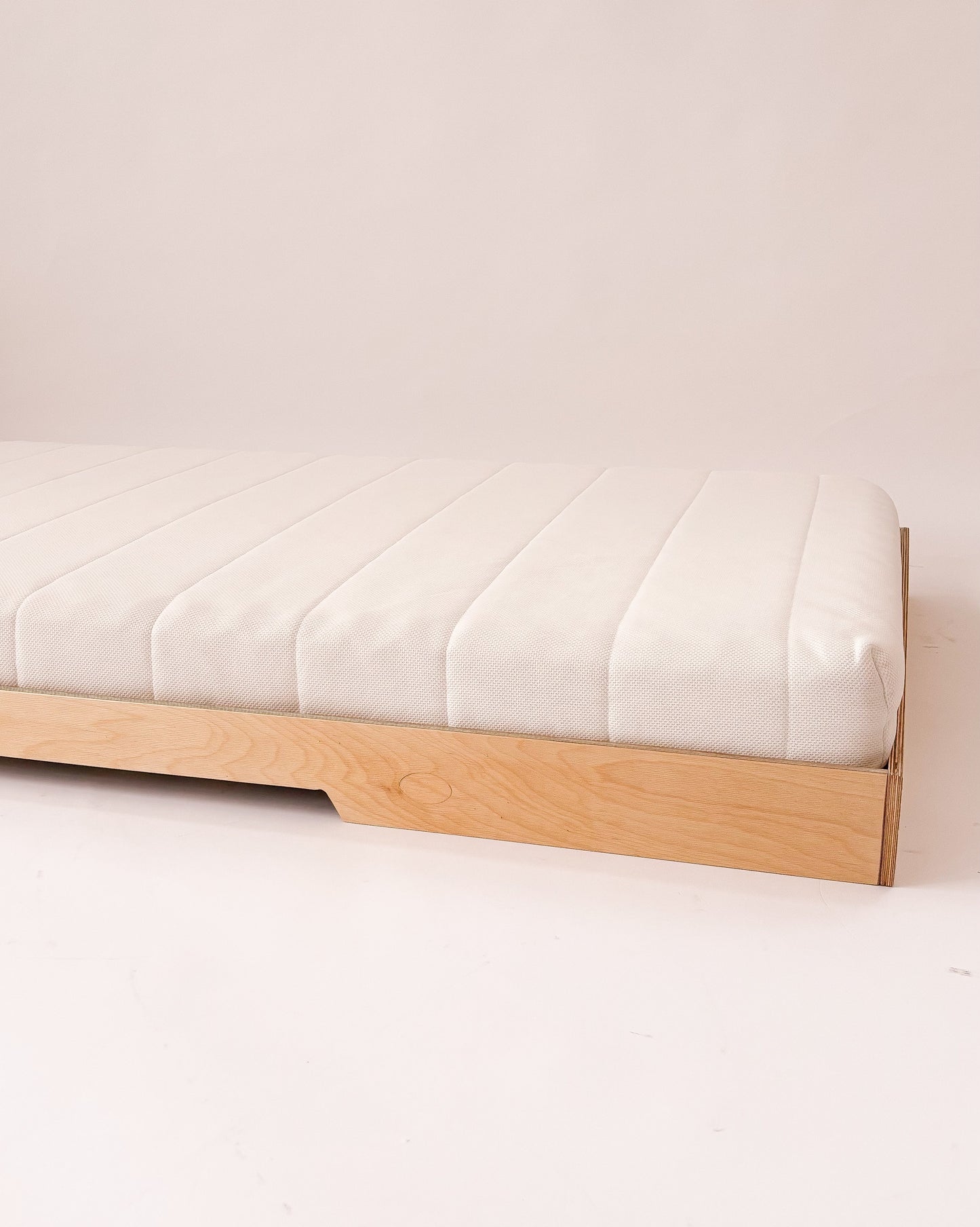 Cama Montessori de madeira com estrutura baixa e sem grades, ideal para autonomia infantil.