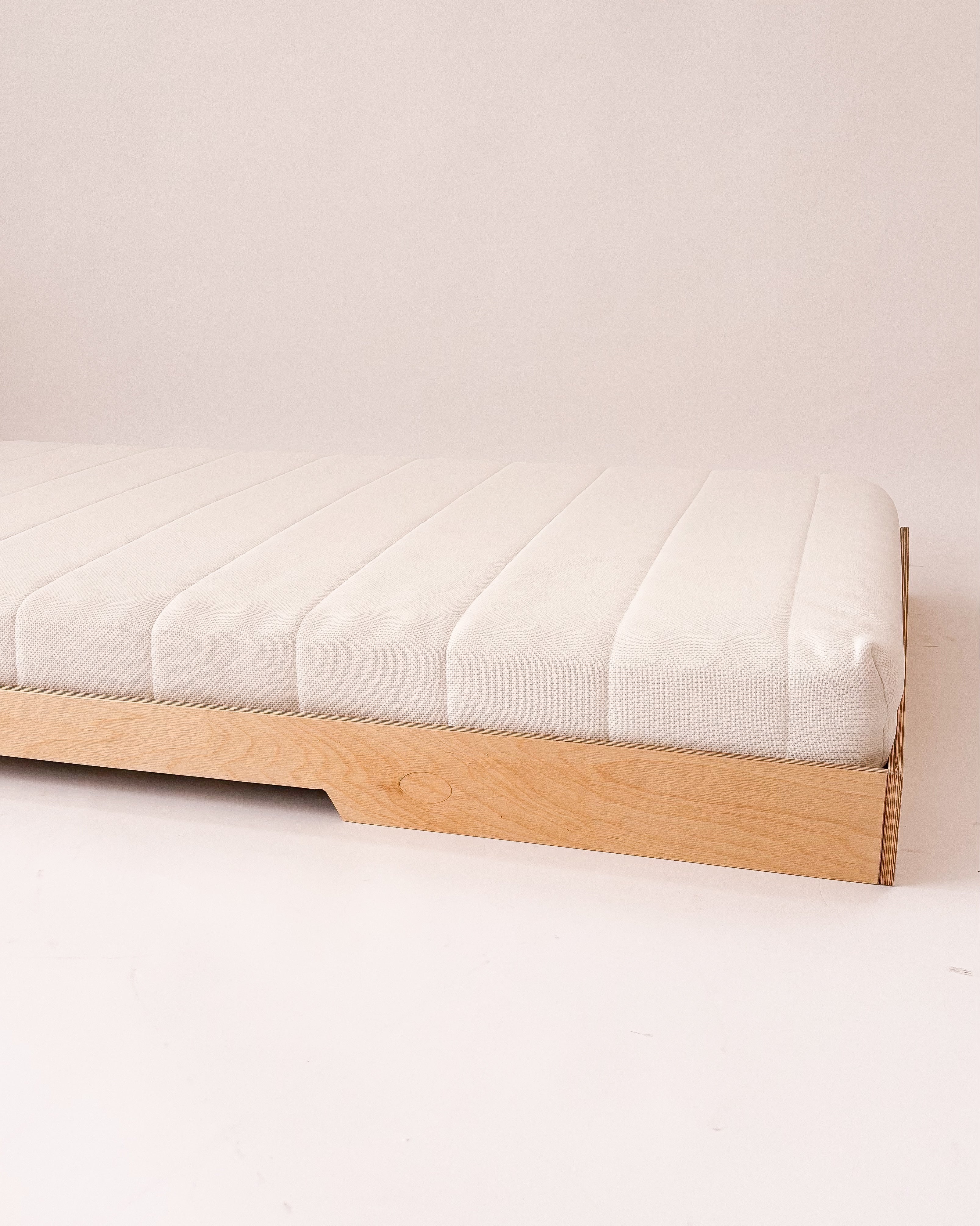 Cama Montessori de madeira com estrutura baixa e sem grades, ideal para autonomia infantil.