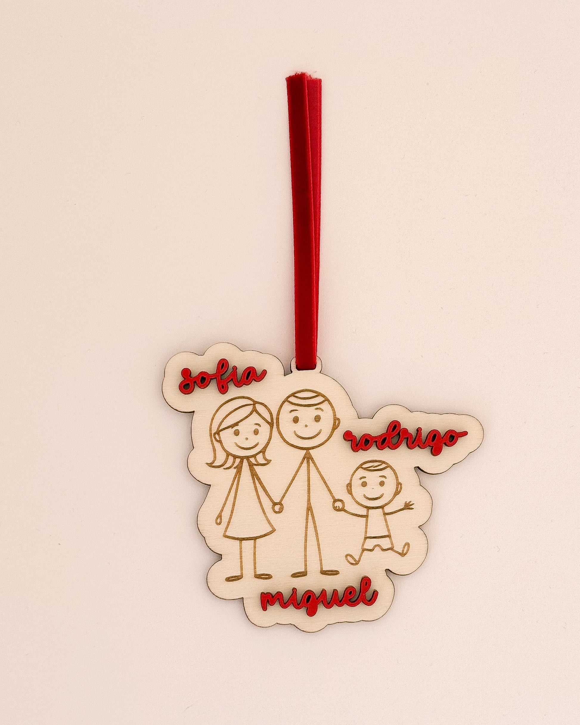 Pendente de Natal personalizado em madeira com desenho de família e nomes gravados, com fita vermelha – feito em Portugal pela TOCA.