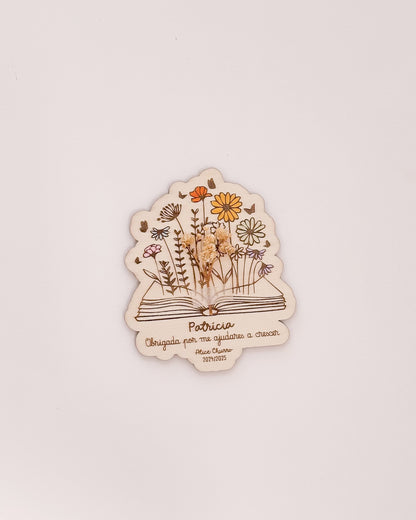 Placa de agradecimento para professores com nome gravado e arranjo de flores secas.